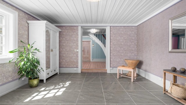 Hallen er pusset opp i selgers eiertid, og har nå stilrene store fliser som passer godt inn i boligens estetikk