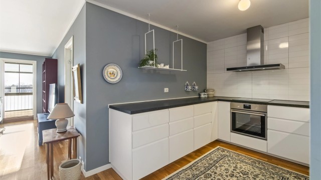 Innredningen er moderne og delikat i lys utførelse. Det er rikelig med skap- og benkeplass. Flisplater er montert på veggen over benkeplaten.