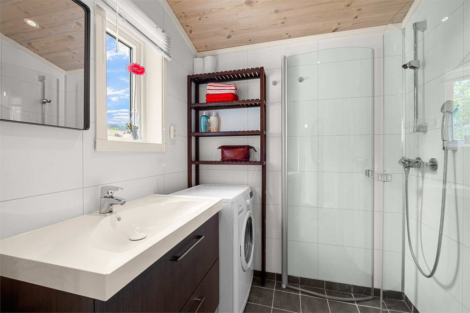 Badet er innredet med servantskap med speil, dusjhjørne, vegghengt toalett og plass til vaskemaskin. Det er også etablert varmekabler på badet.