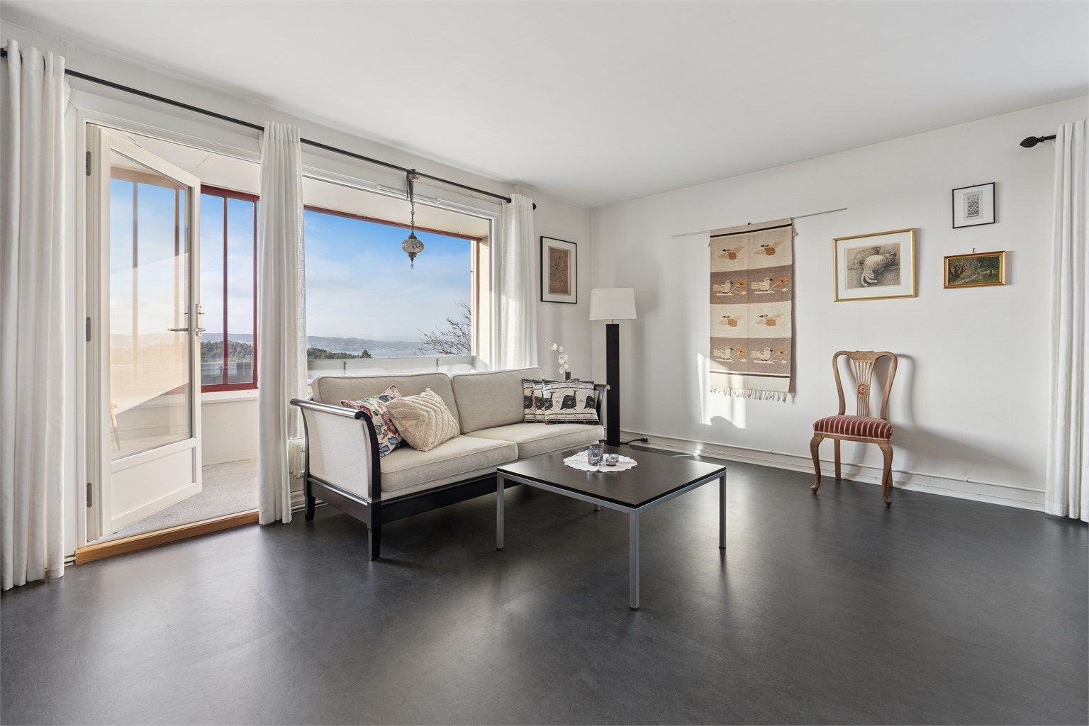 Store vindusflater og direkte utgang til balkongen gir stuen en åpen og luftig atmosfære.