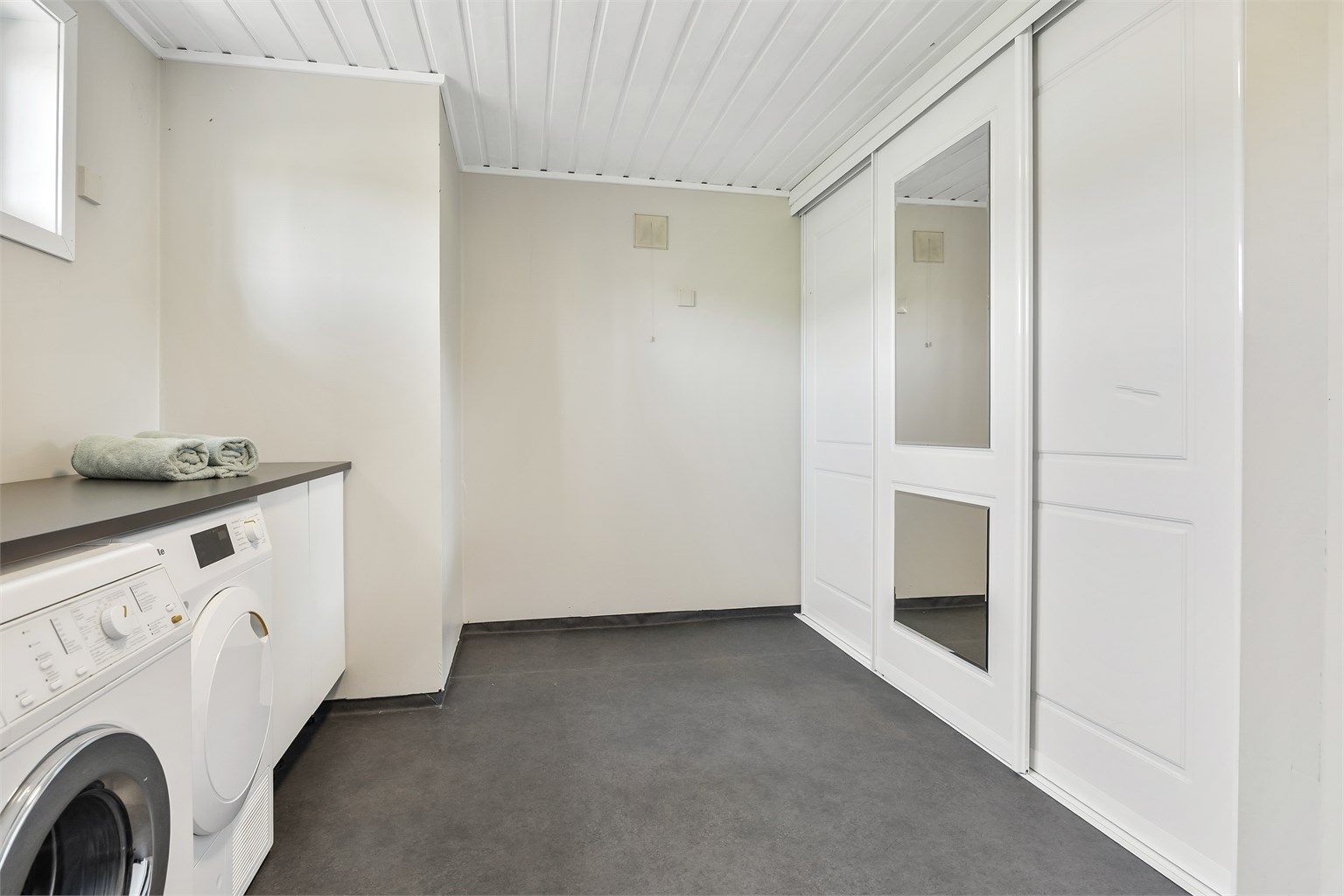 Rommet har opplegg for vaskemaskin/tørketrommel under benk og god lagringsplass i skyvedørsgarderobe.