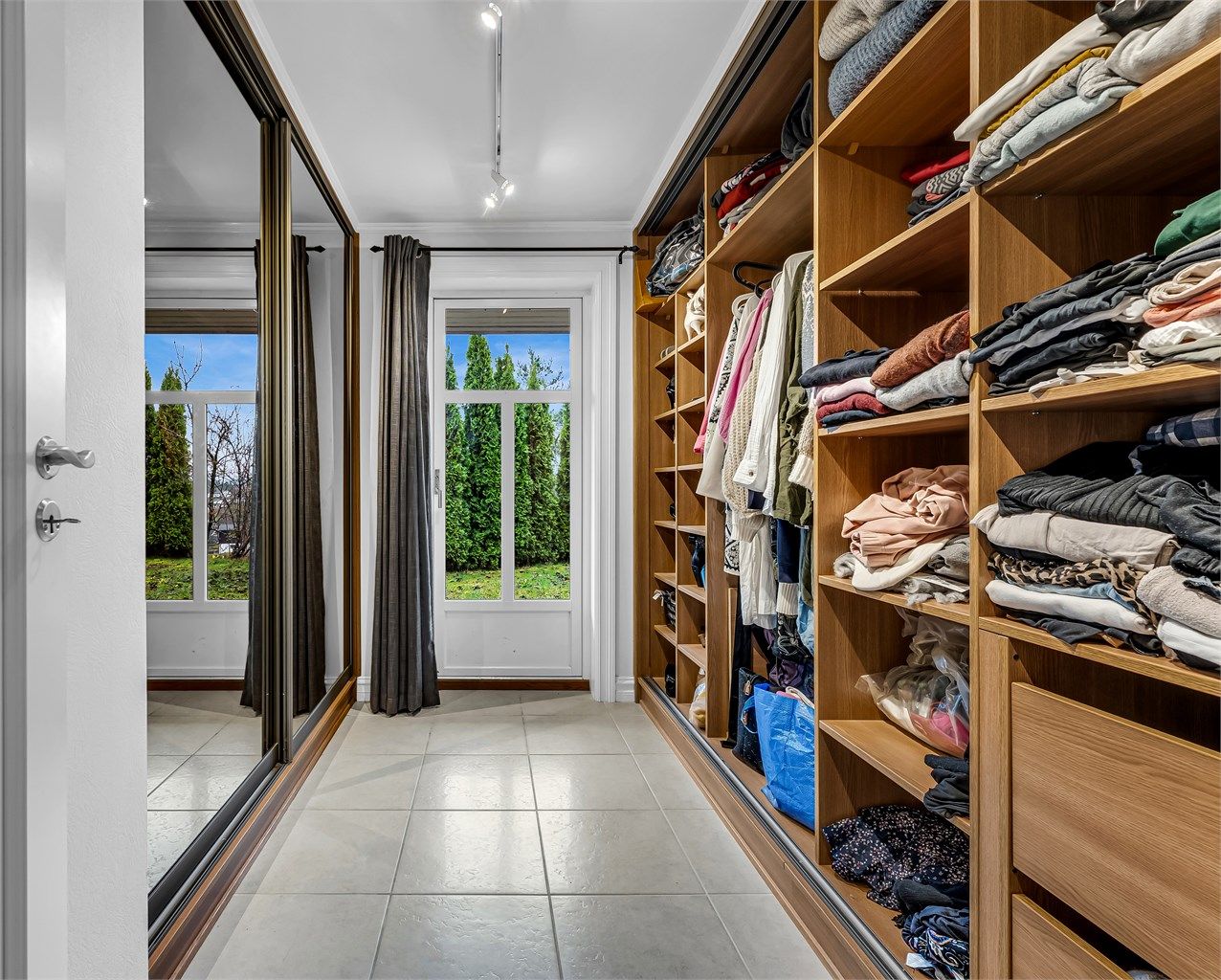 Praktisk walk-in-closet med god garderobeplass og speildører, samt utgang til hagen.