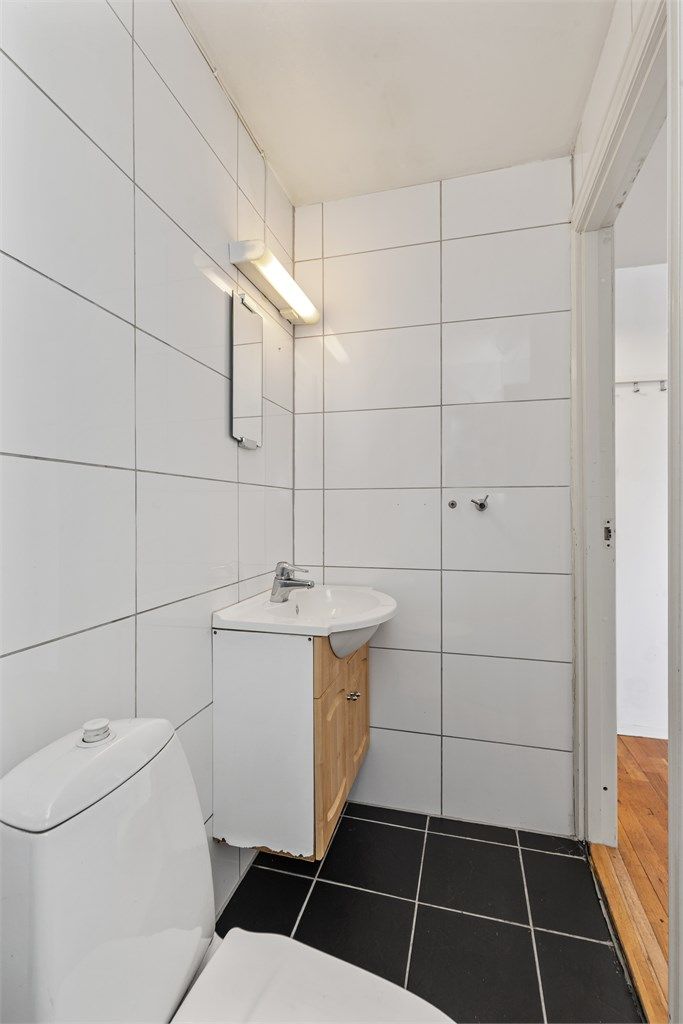 Badet er innredet med servant, speil og belysning, samt gulvmontert toalett.