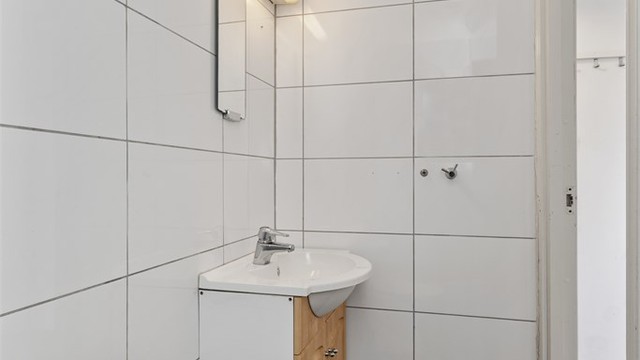 Badet er innredet med servant, speil og belysning, samt gulvmontert toalett.