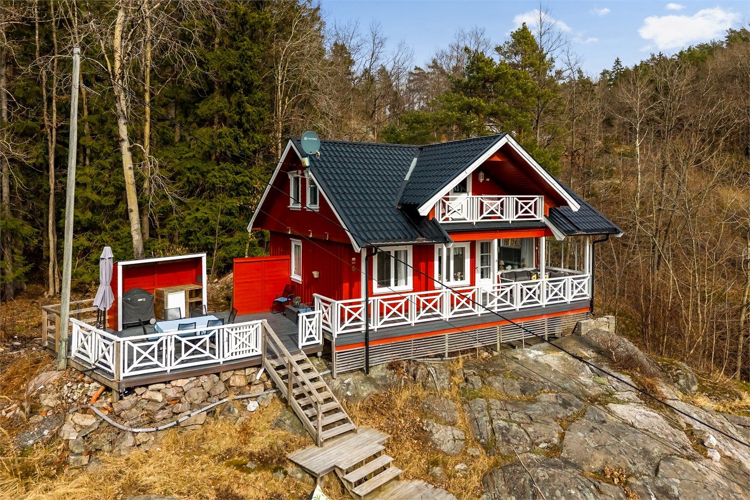 Tilbaketrukket sommersted. Den rødmalte hytta ligger på en kolle helt for seg selv med anneks nedenfor.