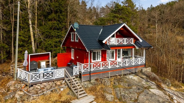 Tilbaketrukket sommersted. Den rødmalte hytta ligger på en kolle helt for seg selv med anneks nedenfor.