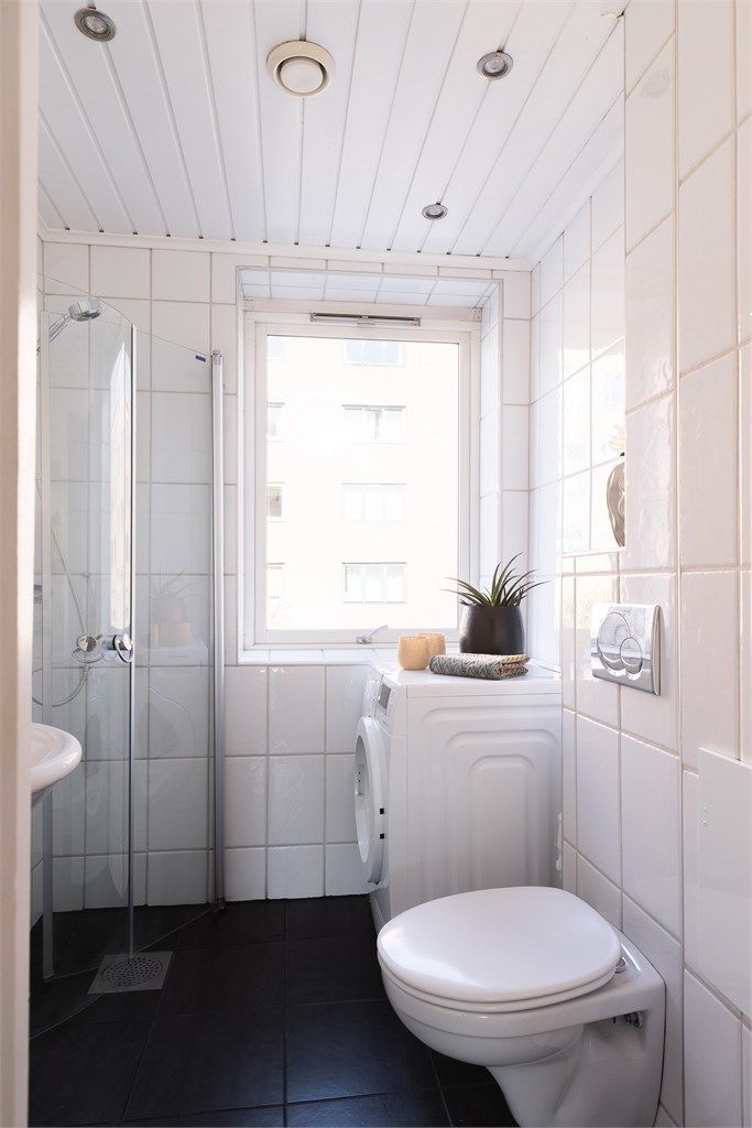Badet er utstyrt med vegghengt toalett og dusjhjørne med svingbare glassdører.