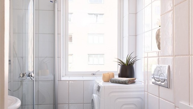 Badet er utstyrt med vegghengt toalett og dusjhjørne med svingbare glassdører.