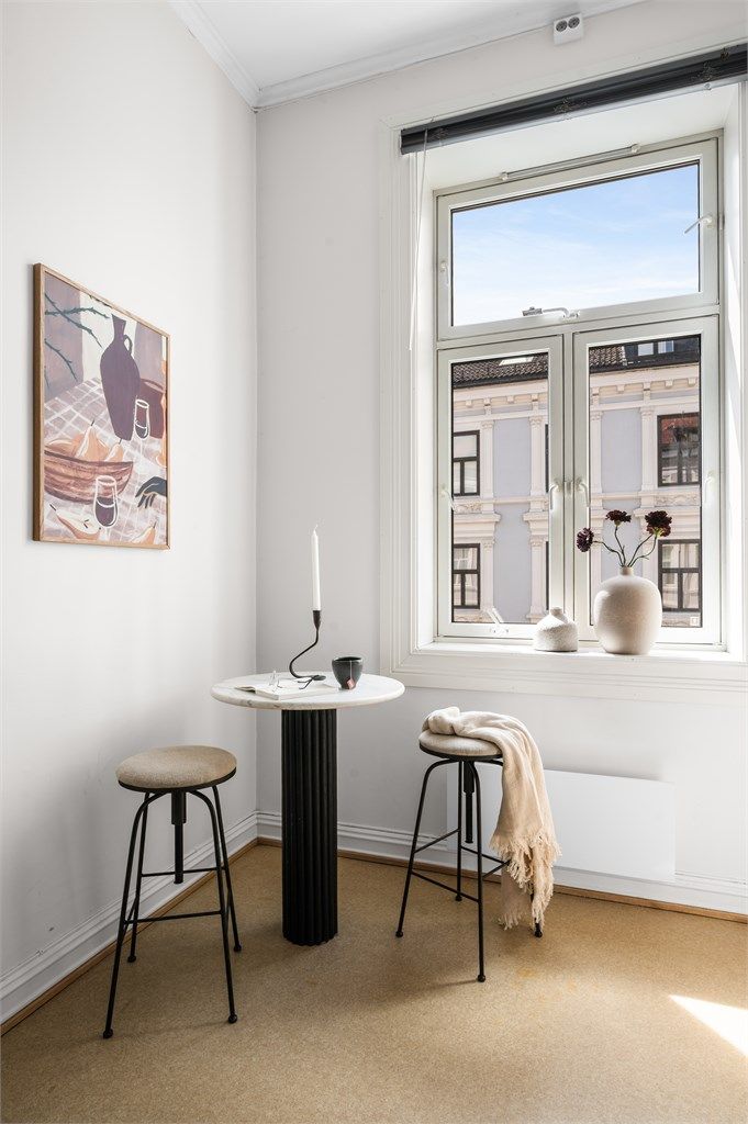 Et naturlig sted for morgenkaffen, med dagslys fra vinduet og utsyn mot den klassiske bygårdsbebyggelsen.
