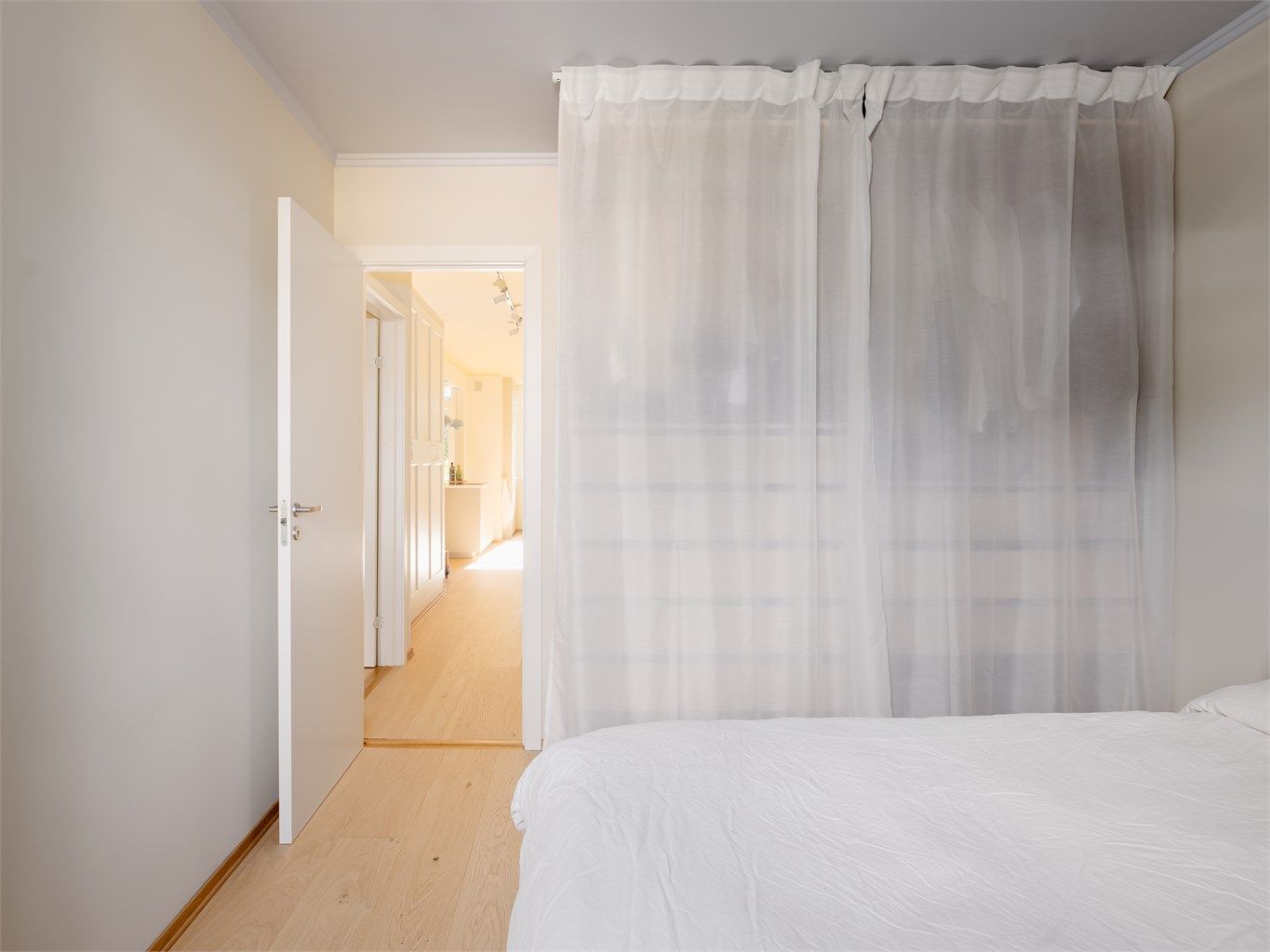 Bak de luftige gardinene finner du et vell av oppbevaring, og rommet flyter sømløst videre inn i resten av boligen – alt er mykt og gjennomtenkt her hjemme!