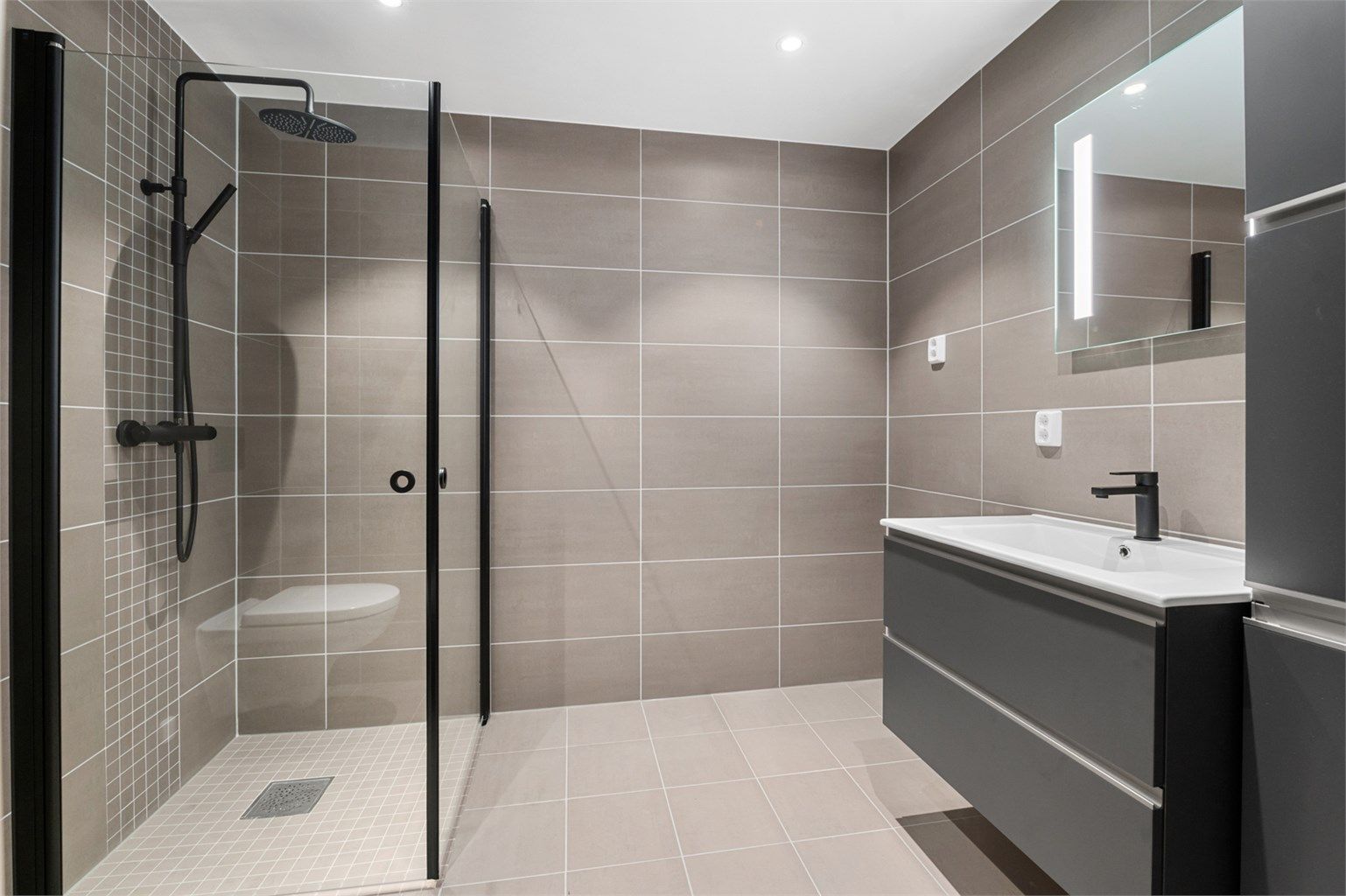 Badet inneholder blant annet servantskap, speil med innebygd lys, vegghengt toalett, opplegg for vaskemaskin og downlights i himling.