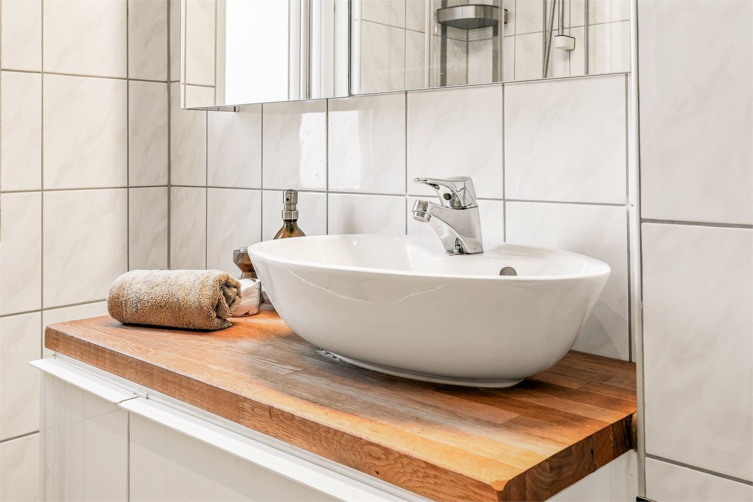 Badet har vegghengt servantinnredning, speilskap med overlys, vegghengt baderomsmøbel for oppbevaring og vegghengt toalett.