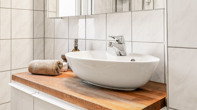 Badet har vegghengt servantinnredning, speilskap med overlys, vegghengt baderomsmøbel for oppbevaring og vegghengt toalett.