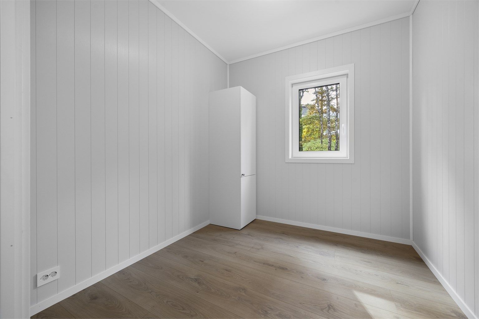 Soverom med plass til seng og garderobeskap, vendt mot grønne omgivelser.