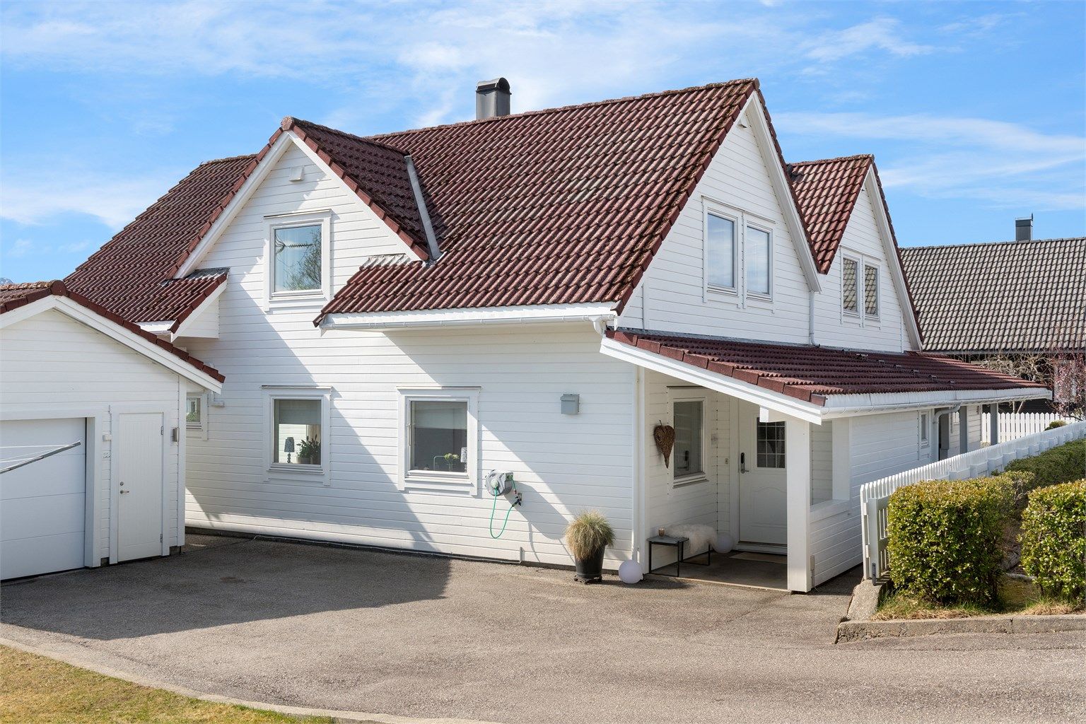 Asfaltert gårdsplass med parkering foran boligen og garasjen