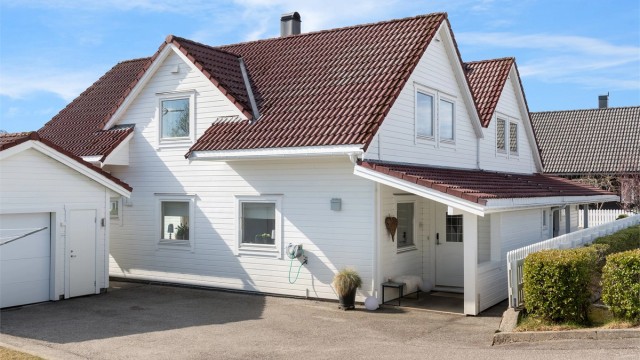 Asfaltert gårdsplass med parkering foran boligen og garasjen