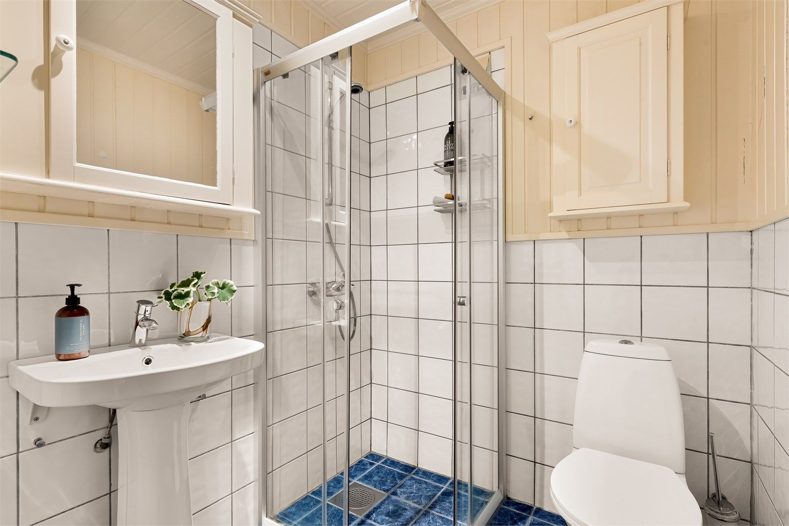 Bad tilknyttet utleiedelen mot øst. Badet har flislagt gulv med gulvvarme, en kombinasjon av panel og flis på veggene samt et praktisk dusjhjørne.