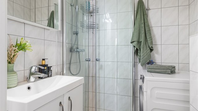 Lyst og pent bad med praktisk løsning og varmekabler i gulv.