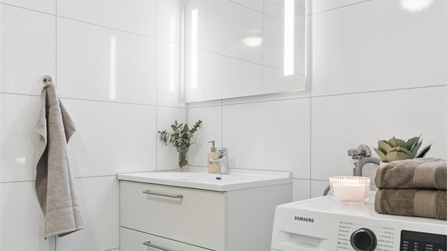 Badet har vinylbelegg på gulvet med elektriske varmekabler og baderomspaneler på veggene.