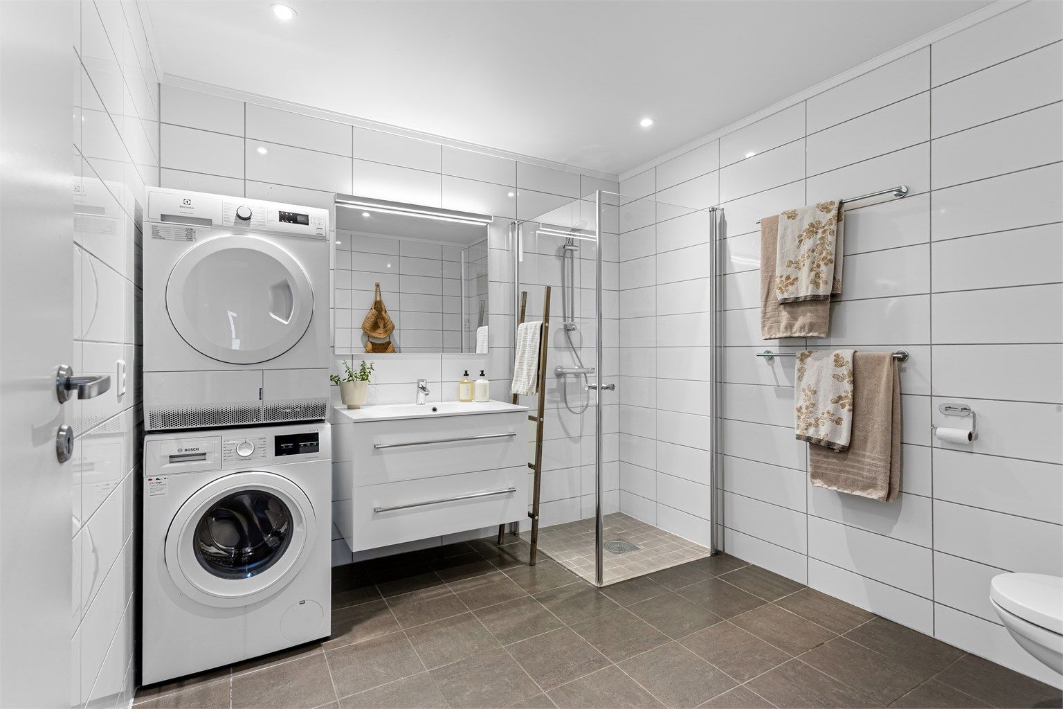 Stor bad. Flislagt gulv med gulvvarme. Downlights i himlingen. Innredet med vegghengt servantskap med skuffer og ovenpåliggende servant.