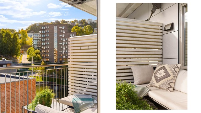 Balkongen har terrassebord på gulvet, skjermende spilevegg og rekkverk i metall, som gir uteplassen et gjennomført uttrykk.