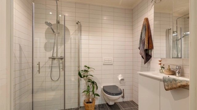 Badet i hovedetasjen har også vegghengt toalett, innfellbare glassdører i dusjen, og servant med speilskap over samt skap under. Downlights i himling.