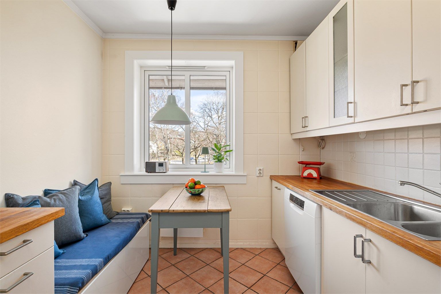 Separat kjøkken med plass til spisebord og sittebenk ved vinduet. Fra vinduet er det koselig utsyn over nabolaget og opp mot Grefsenåsen