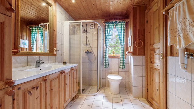 Bad med flislagt gulv med varmekabler, dusjhjørne og opplegg for vaskemaskin.
