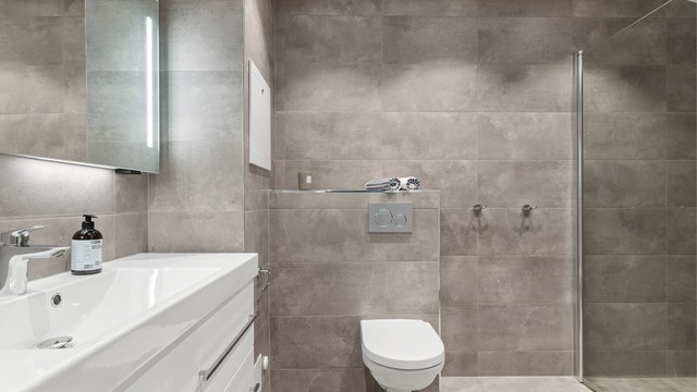 Romslig og innbydende familiebad fra 2018 med moderne standard og praktiske løsninger. Badet har flislagt gulv med gulvvarme, flislagte vegger og nedsenket himling med downlights som gir behagelig belysning.