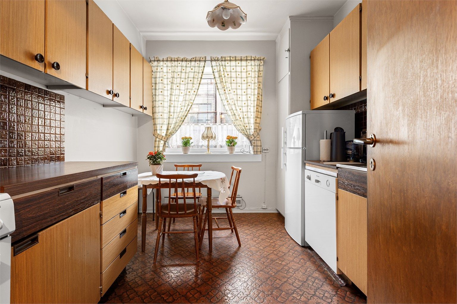 Kjøkkenet har en eldre innredning med glatte fronter og benkeplate i laminat med nedfelt vask. 