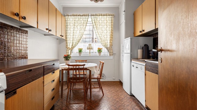 Kjøkkenet har en eldre innredning med glatte fronter og benkeplate i laminat med nedfelt vask.