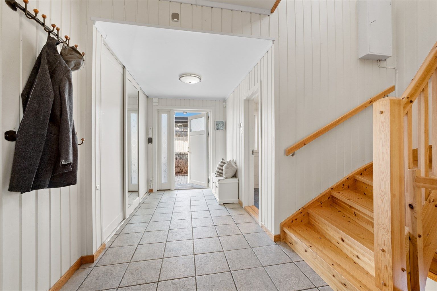 Man kommer inn i en romslig entré med flislagt gulv og varmekabler.