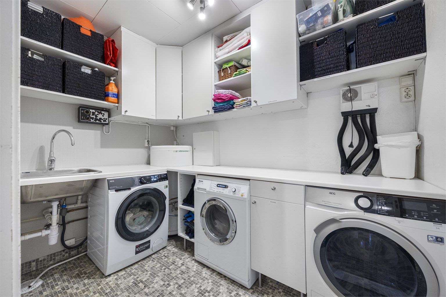 Praktisk vaskerom med god benke- og skapplass, utslagsvask og opplegg for vaskemaskin. 