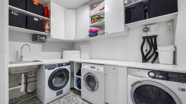 Praktisk vaskerom med god benke- og skapplass, utslagsvask og opplegg for vaskemaskin.