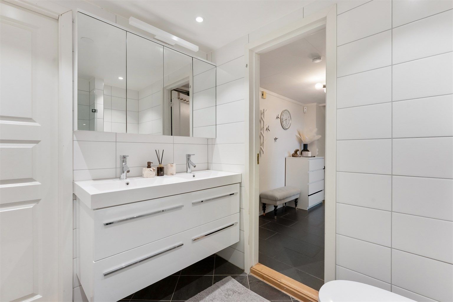 Pent baderom fra 2013 med fliser på gulv med gulvvarme, fliser på vegger og malt himling med downlights
