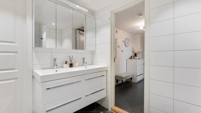 Pent baderom fra 2013 med fliser på gulv med gulvvarme, fliser på vegger og malt himling med downlights