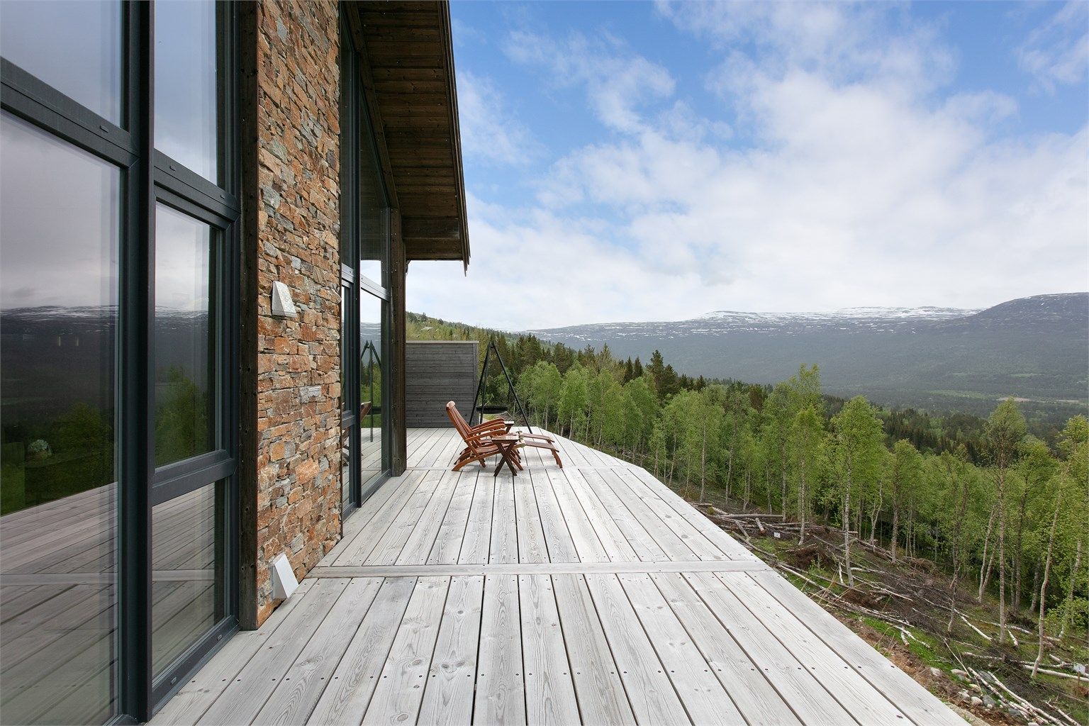 Det romslige terrassedekket strekker seg langs hyttens sørside med fri sikt over terrenget.