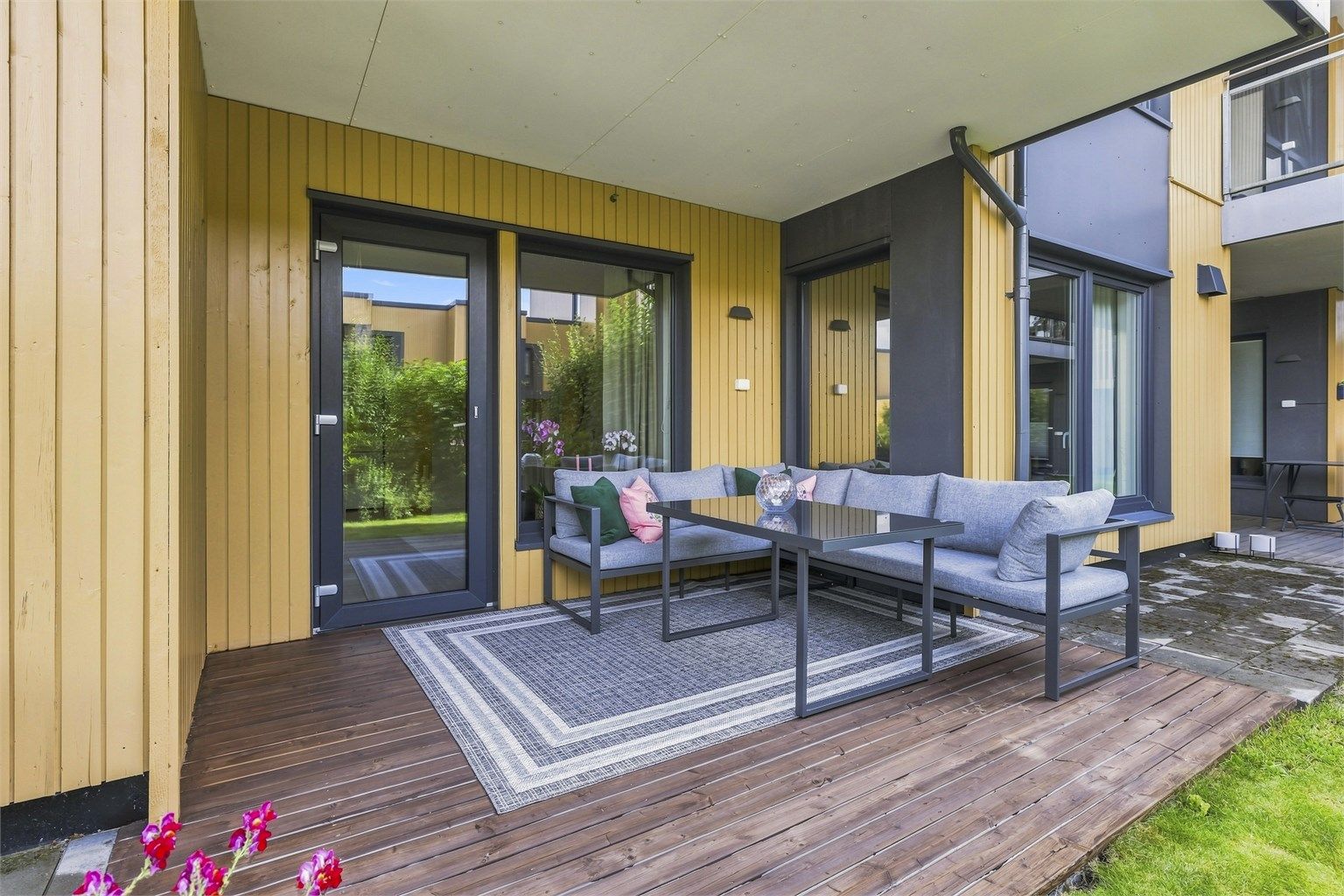 Terrasse i trekonstruksjoner. Gulvoverflater belagt med terrassebord. Terrassen har utebelysning og utvendig stikkontakt. Ved siden av markterrassen er det ytterligere plass til diverse på betongheller. Foto: Marikafoto / Marika Mørkestøl 