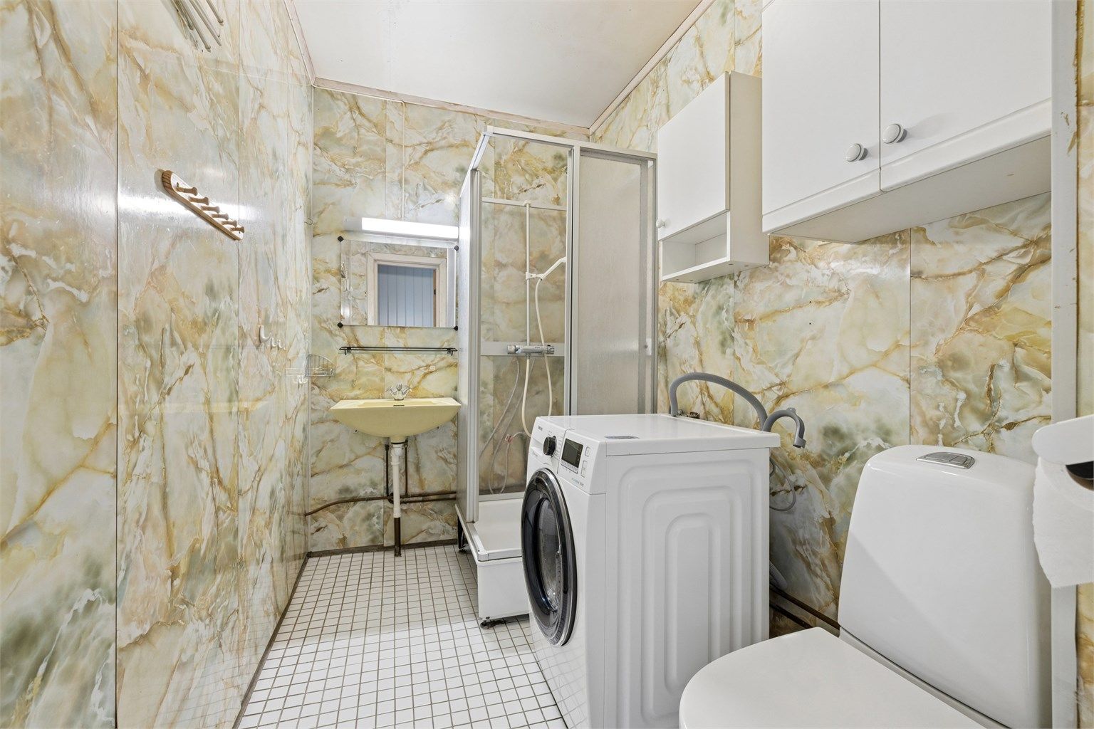 Badet i andre etasje har våtromsplater på veggene, dusjkabinett og opplegg for vaskemaskin.