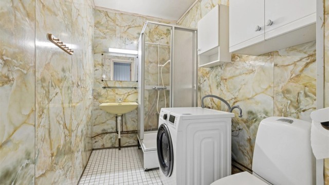 Badet i andre etasje har våtromsplater på veggene, dusjkabinett og opplegg for vaskemaskin.