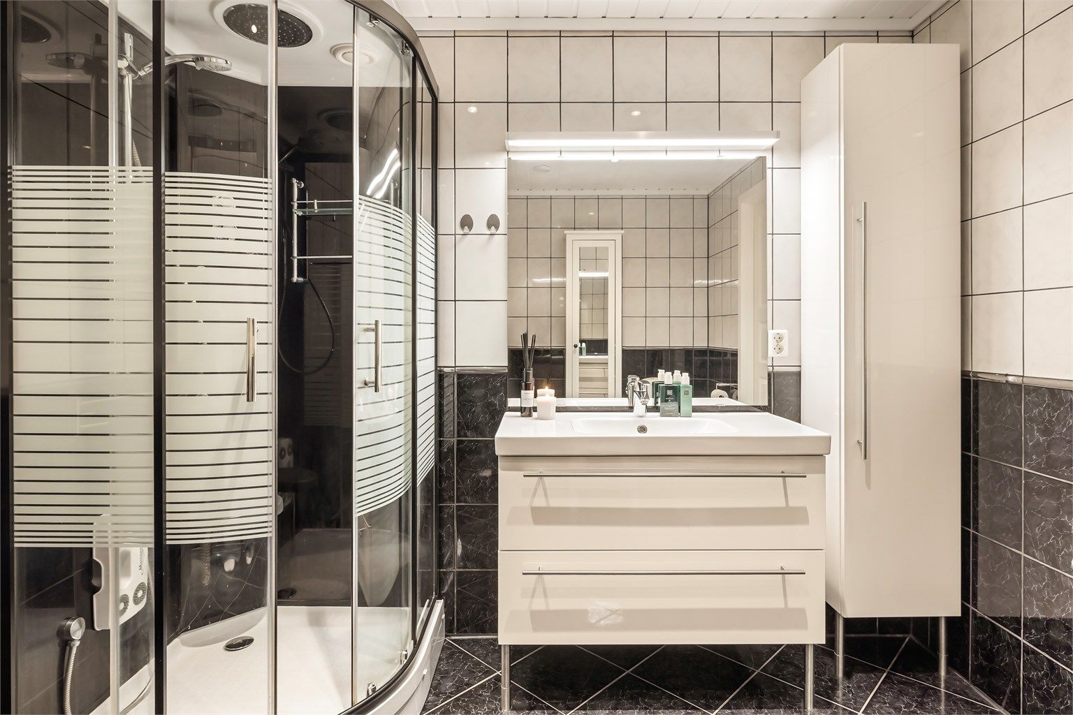 Rommet er utstyrt med dusjkabinett, servantinnredning med god oppbevaring og høyskap.