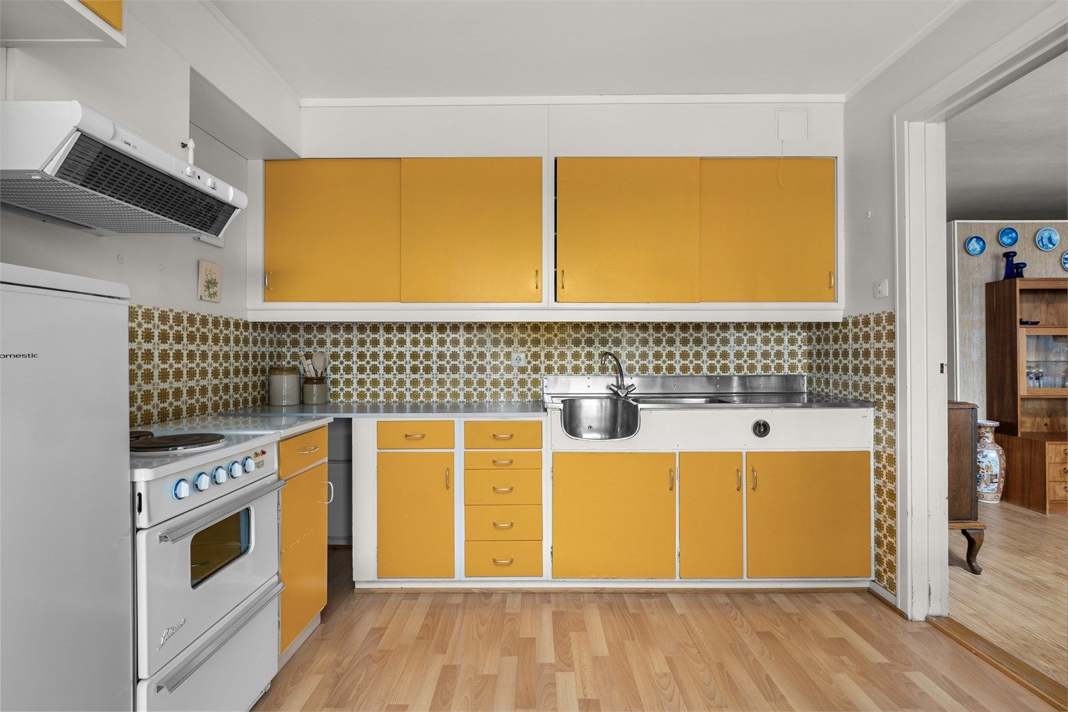 Kjøkkenet har blant annet benkeplate av rustfritt stål med nedfelt oppvaskkum og frittstående komfyr og kjøleskap med fryser.

