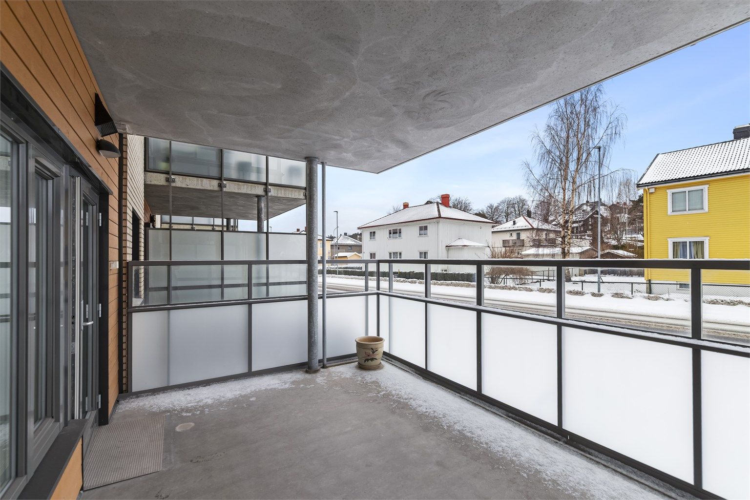 Verandaen ligger over bakkeplan med høye glassvegger, skjermet for innsyn