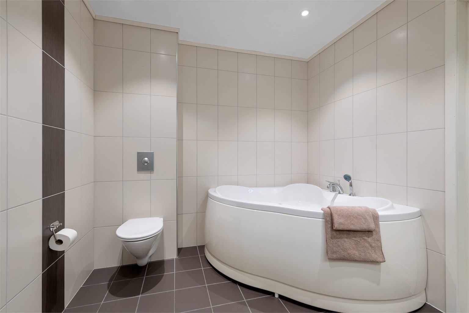 Rommet har downlights i taket, vegghengt toalett og er fra byggeåret.