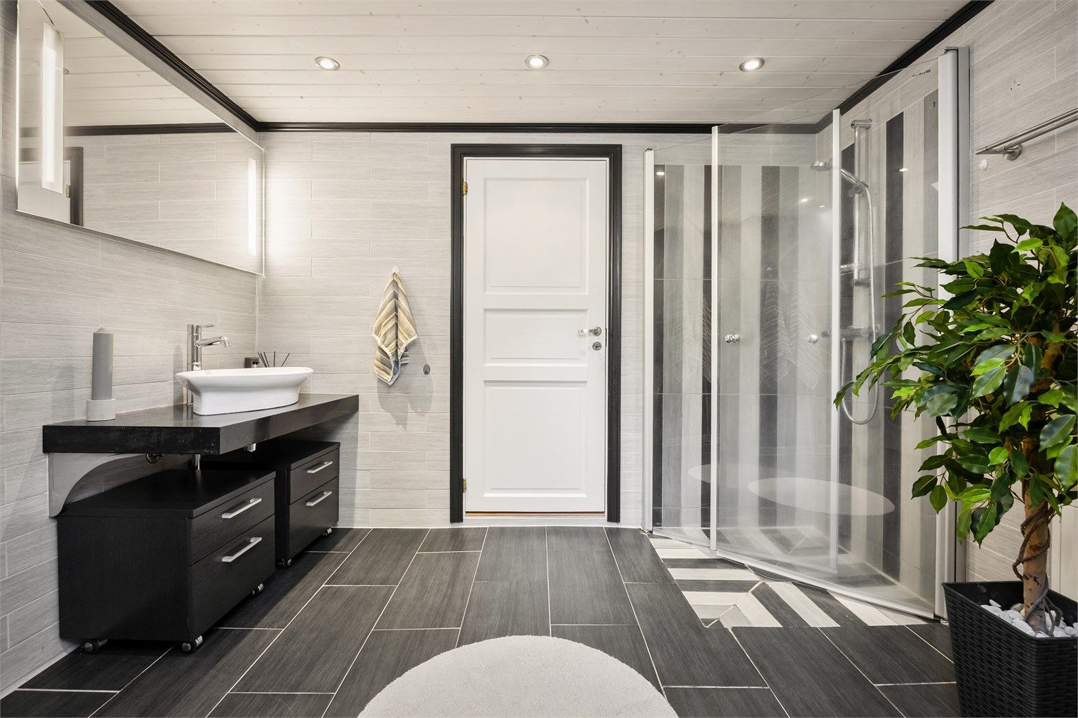 Badet har dusjhjørne med innfellbare dører av glass.