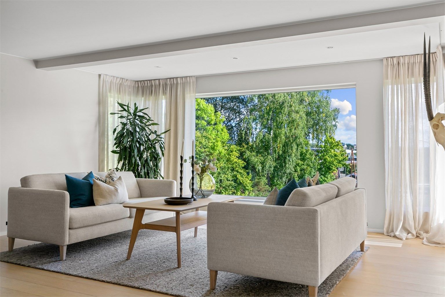 Romslig stue med parkett på gulv og god plass til sofagruppe.