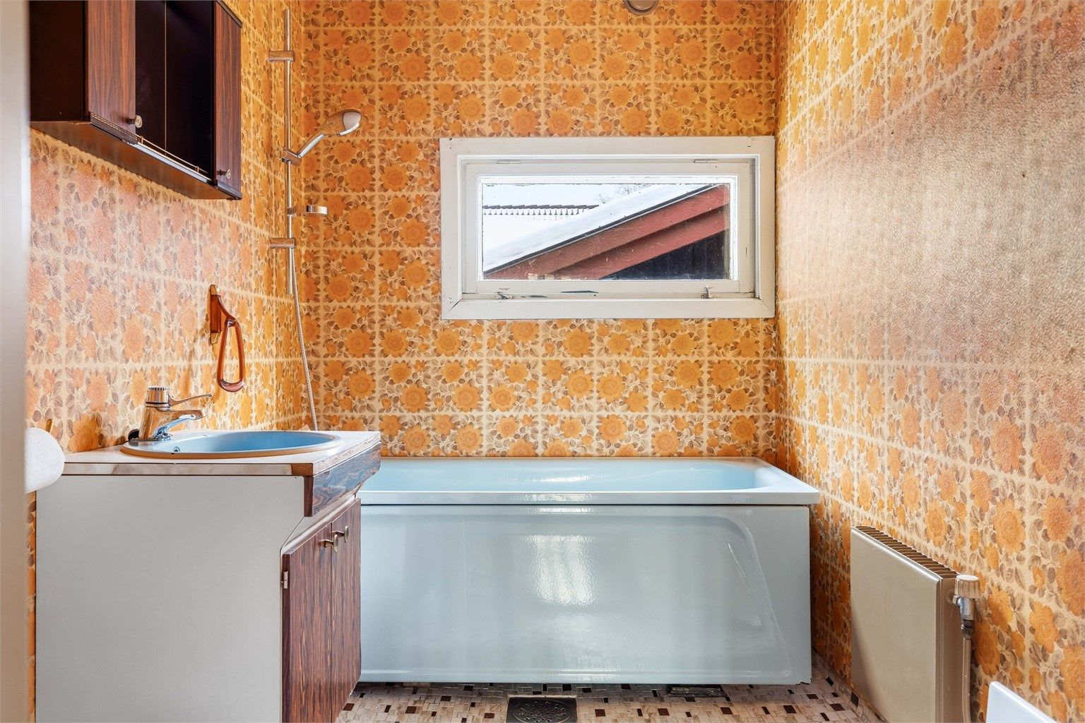 Badet har flislagt gulv og tapetserte veggflater.