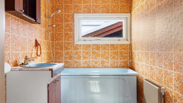 Badet har flislagt gulv og tapetserte veggflater.