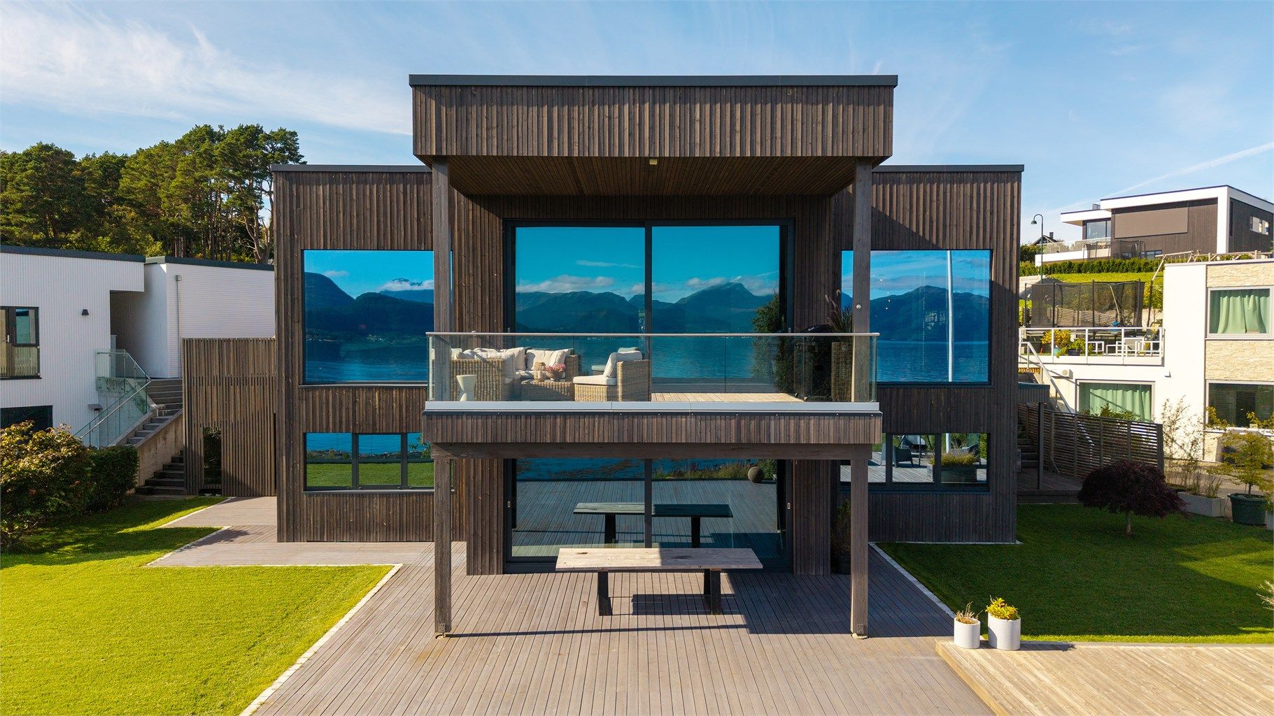 Funkisboligens arkitektur med overbygd balkong og markterrasse mot sjøen.