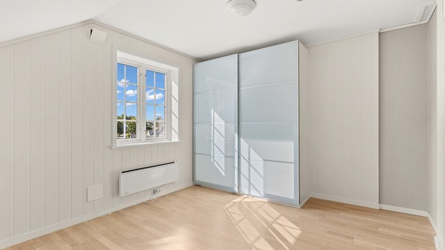 Skyvedørsgarderoben med glassfronter gir rikelig med lagringsplass for klær.